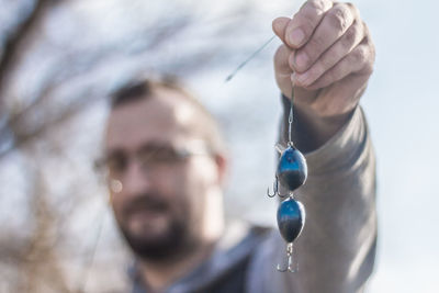 Close-up of man holding blue fishing bait