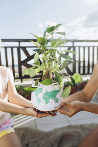 Mother and daughter holding potted plant on roof terrace