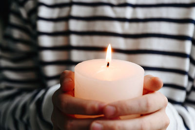 Cropped hands holding lit candle