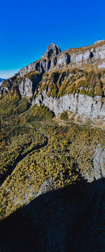 Low angle view of rocky mountains against clear blue sky