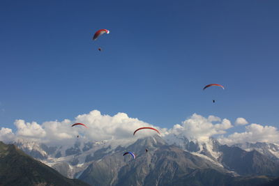 People paragliding by mountains against sky