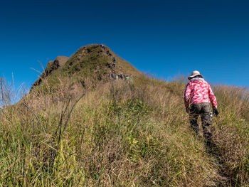 Rear view of woman on field against clear sky