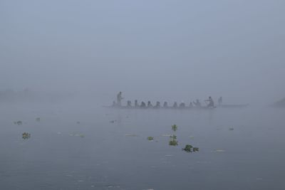 View of tourists in water against sky in foggy weather