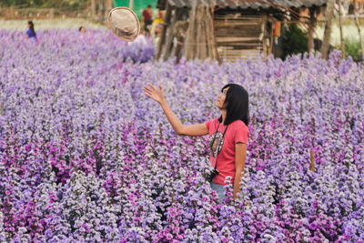 Rear view of woman standing on purple flowering plants