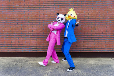 Full length of women standing against pink wall