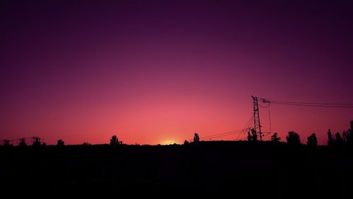 Silhouette electricity pylon against sky during sunset