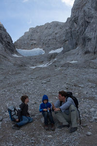 Father with sons sitting against rocky mountains