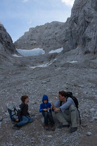 Men sitting on mountain road against sky