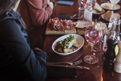 Midsection of woman having food with friend in restaurant