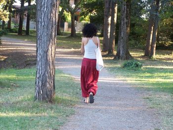 Rear view of woman walking along trees