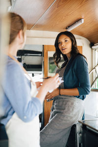 Female owner talking to coworker while standing in food truck