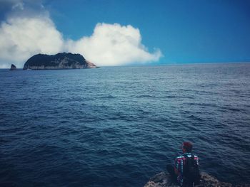 Rear view of people on sea against sky