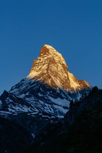 Low angle view of rock formation against clear blue sky