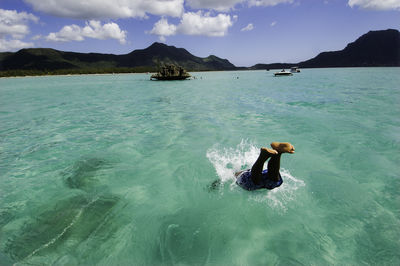 Rear view of woman swimming in sea against sky