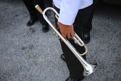 Midsection of man holding trumpet while standing on road