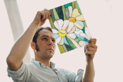 Portrait of young woman holding gift against white background