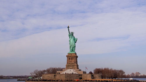 Low angle view of statue of liberty against cloudy sky