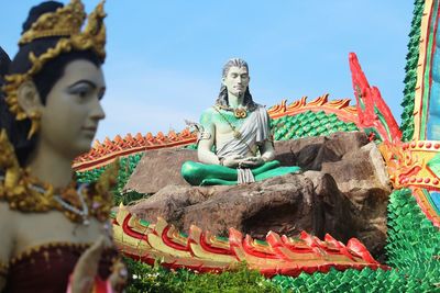 Statue against temple and building against sky