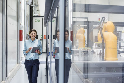 Businesswoman checking robots with digital tablet in high tech company