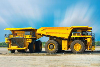 Yellow vehicle at construction site against sky