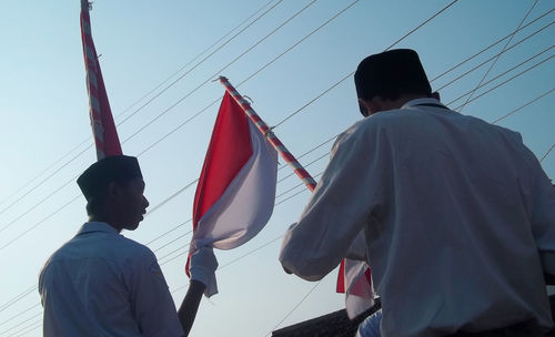 Low angle view of man flag against clear sky