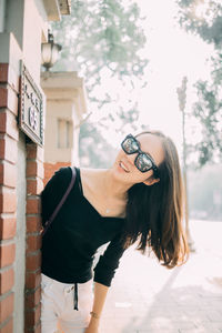 Portrait of young woman standing by wall