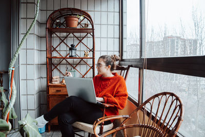 Portrait of young woman sitting on chair at home