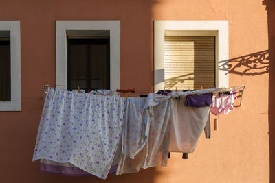 Laundry drying by windows outside house