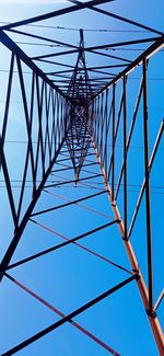 Low angle view of electricity pylon against clear blue sky