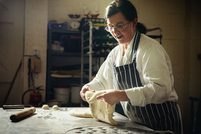 Female baker preparing bread dough in commercial kitchen