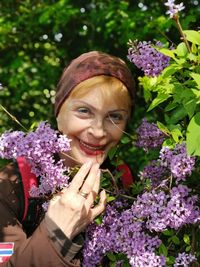 Portrait of a smiling young woman against purple flowering plants