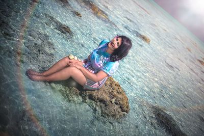 Young woman on rock by sea