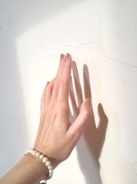 Cropped hand of woman against wall