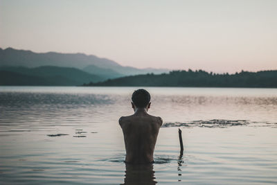 Rear view of shirtless man in lake