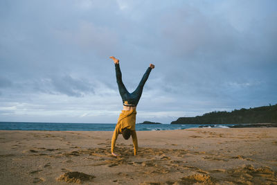 Full length of man with arms raised on beach against sky