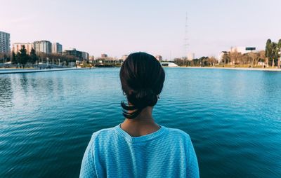 Rear view of woman looking at cityscape against sky