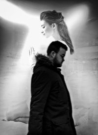 Side view of young couple standing against wall
