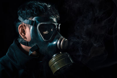 Close-up of man wearing mask against black background