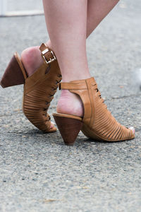 Low section of woman wearing sandal while standing on street