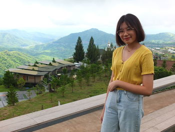 Young woman standing on mountain against trees and mountains