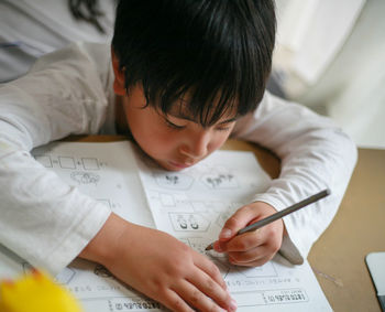 Close-up of boy drawing on blueprint at home