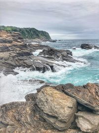 Rock formations on shore against sky