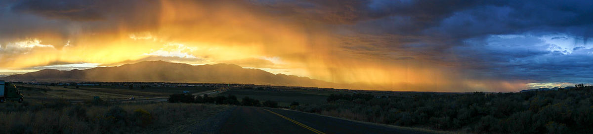 Panoramic view of dramatic landscape against cloudy sky during sunset