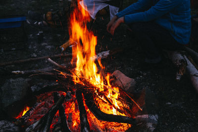 Low section of man sitting by bonfire