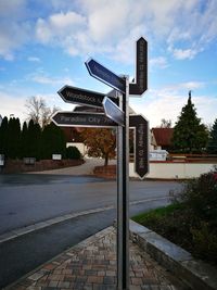 Road sign by city against sky