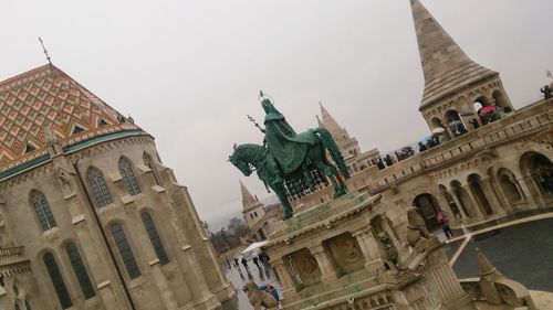 Tilt image of statue amidst historic building against clear sky