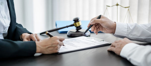 Midsection of real estate agent giving key to client in office