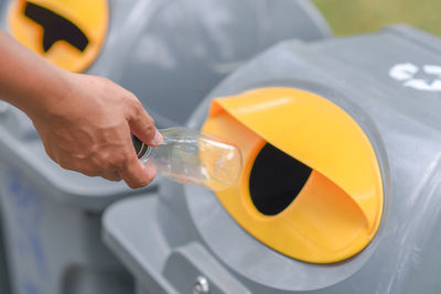 Close-up of hand putting bottles in recycling bin