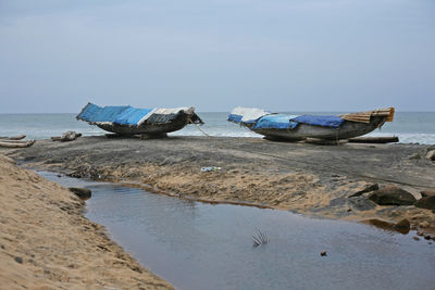 Abandoned boat moored on beach against sky