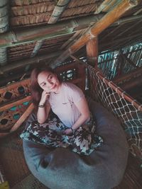 High angle view of young woman looking away while sitting on bean bag at home